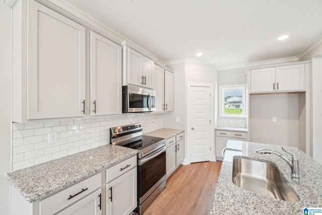 kitchen featuring stainless steel appliances, backsplash, white cabinetry, and sink