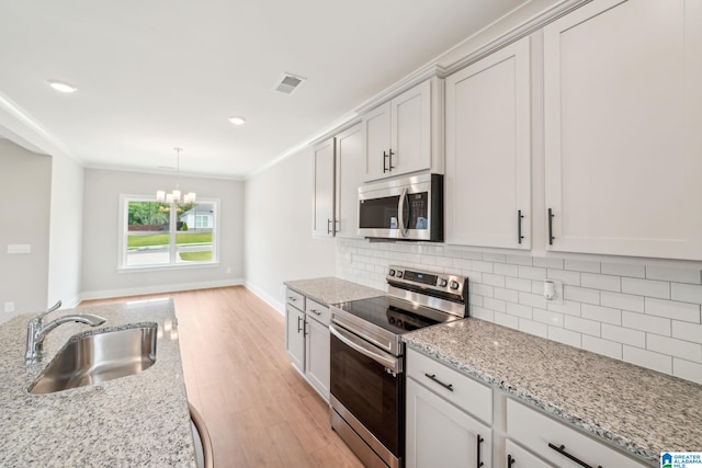 kitchen with stainless steel appliances, decorative backsplash, decorative light fixtures, light stone countertops, and sink