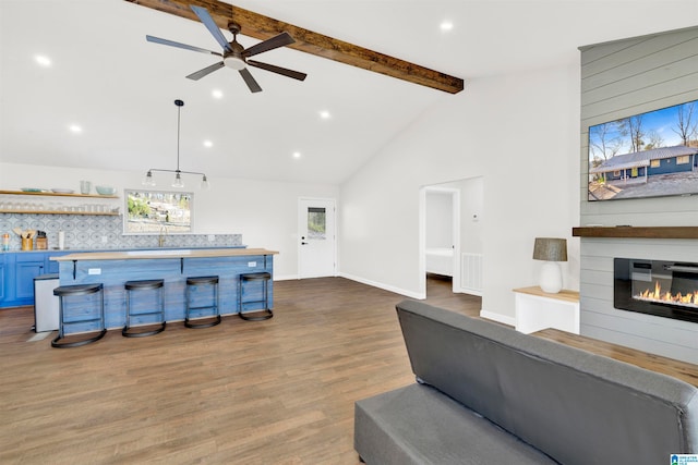 living area featuring beam ceiling, a fireplace, a dry bar, wood finished floors, and baseboards