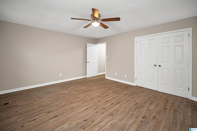 unfurnished bedroom with a closet, ceiling fan, and dark wood-type flooring