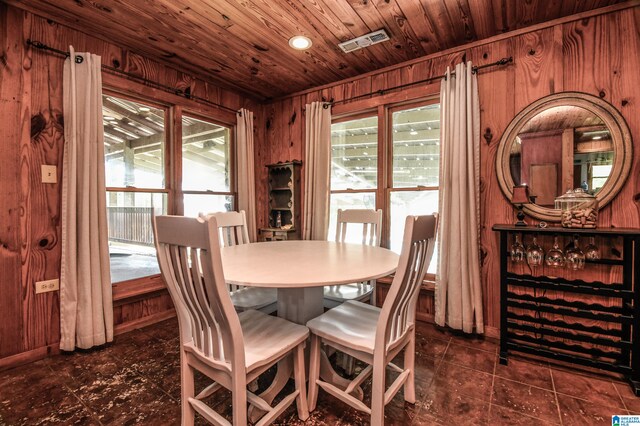 tiled dining space featuring a wealth of natural light, wooden ceiling, and wooden walls