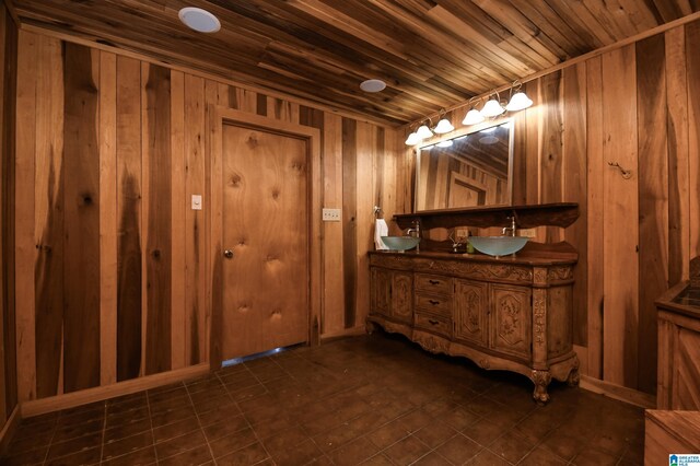 bathroom with dual sinks, wooden ceiling, tile flooring, large vanity, and wooden walls