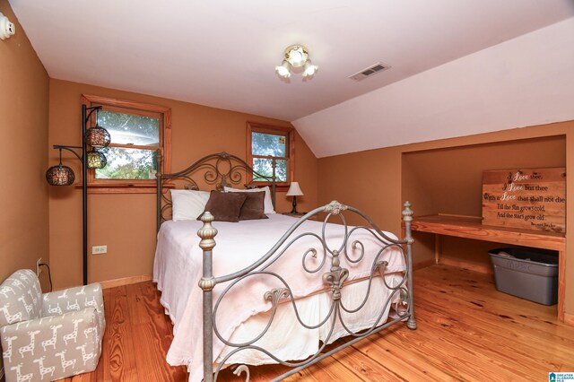 bedroom featuring light wood-type flooring and vaulted ceiling