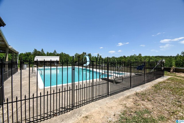 view of swimming pool with a water slide and a patio area