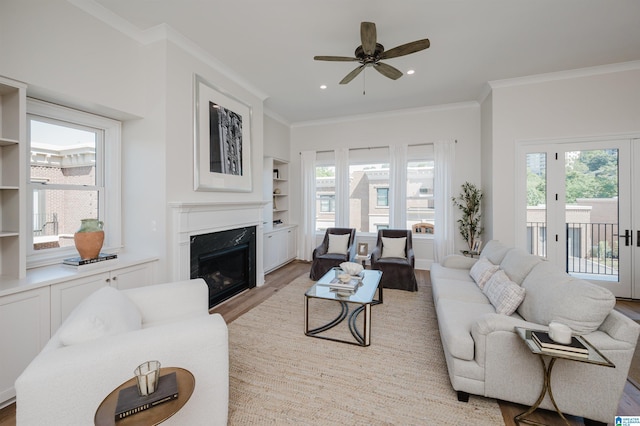living room featuring a high end fireplace, ornamental molding, light wood-style floors, and built in shelves