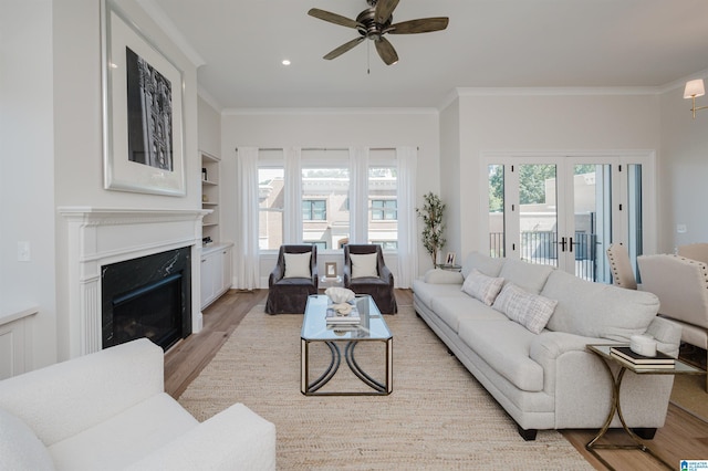 living room with a wealth of natural light, light wood-type flooring, ceiling fan, and a fireplace