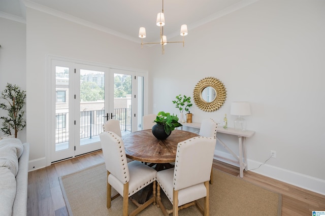 dining area with crown molding, french doors, light wood-type flooring, baseboards, and an inviting chandelier