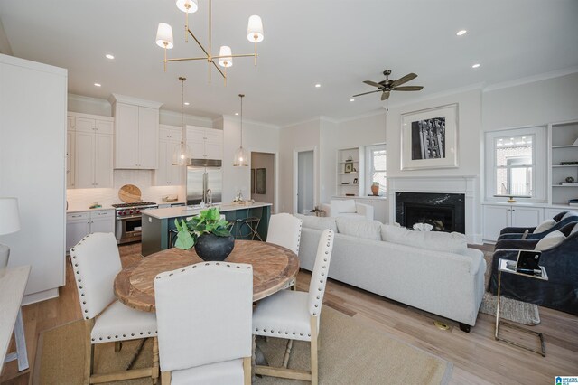 dining space with recessed lighting, ornamental molding, light wood finished floors, ceiling fan, and a high end fireplace