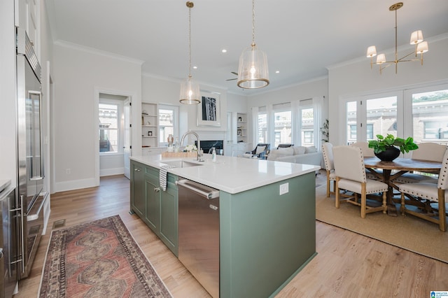 kitchen with light wood-type flooring, a chandelier, a sink, green cabinetry, and appliances with stainless steel finishes
