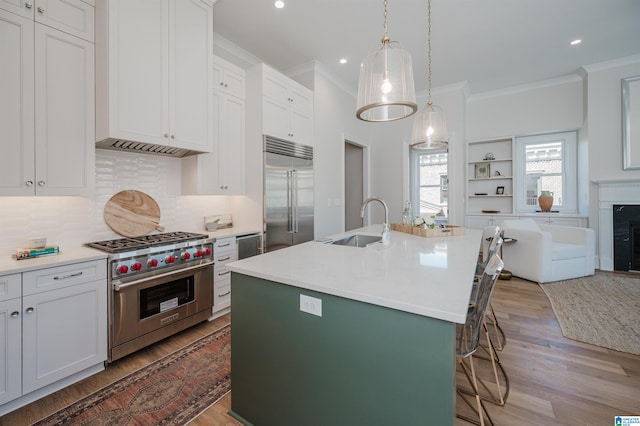 kitchen with a sink, high quality appliances, a kitchen breakfast bar, and crown molding