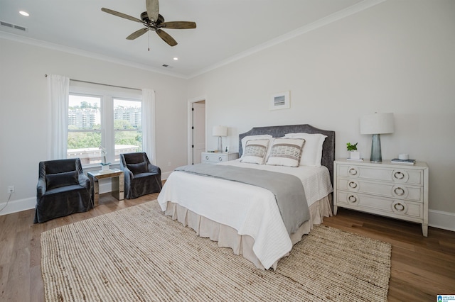 bedroom with wood finished floors, crown molding, baseboards, and visible vents