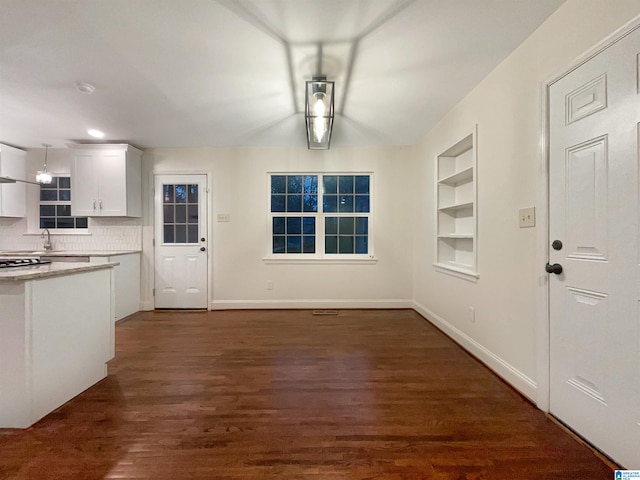 kitchen with built in features, backsplash, white cabinetry, and dark wood-type flooring