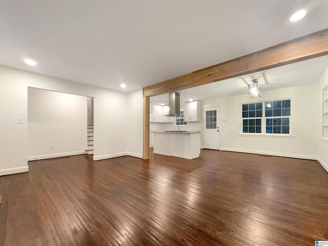 unfurnished living room featuring dark hardwood / wood-style flooring and beamed ceiling