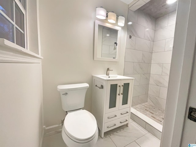 bathroom with tile flooring, toilet, tiled shower, and vanity