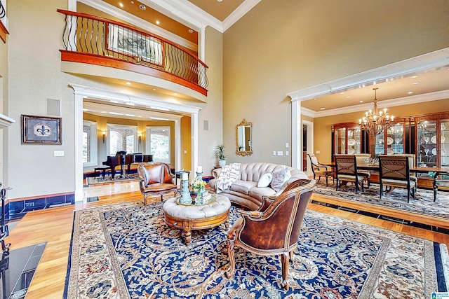 living room featuring ornamental molding, a chandelier, hardwood / wood-style flooring, and a towering ceiling