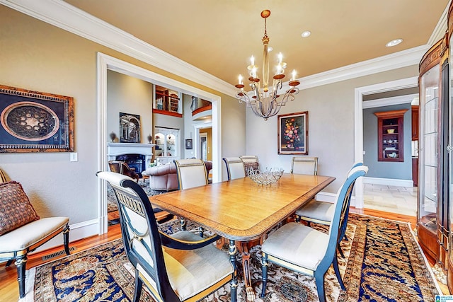 dining room with hardwood / wood-style flooring, ornamental molding, and a chandelier