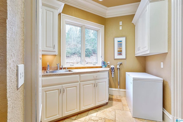 clothes washing area with sink, light tile floors, and ornamental molding