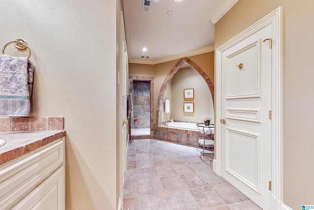 bathroom featuring tile flooring, vanity, crown molding, and tiled bath