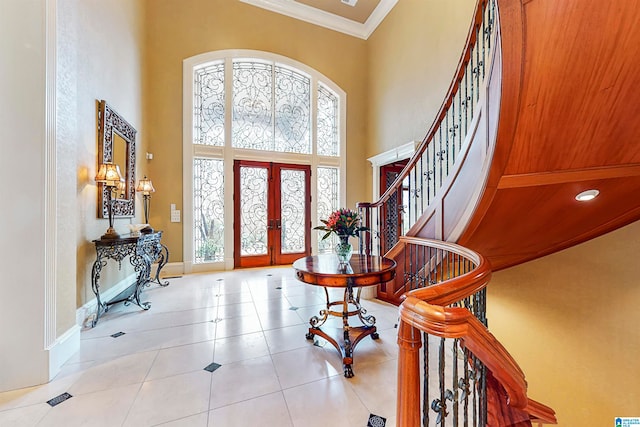 tiled entrance foyer featuring french doors, a towering ceiling, and crown molding