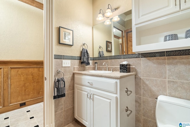 bathroom featuring tile flooring, tile walls, toilet, and large vanity