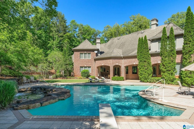 view of swimming pool with a diving board and a patio area