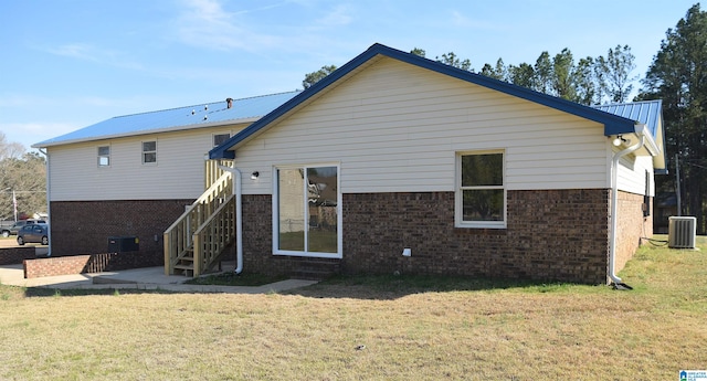 back of house with central air condition unit and a lawn