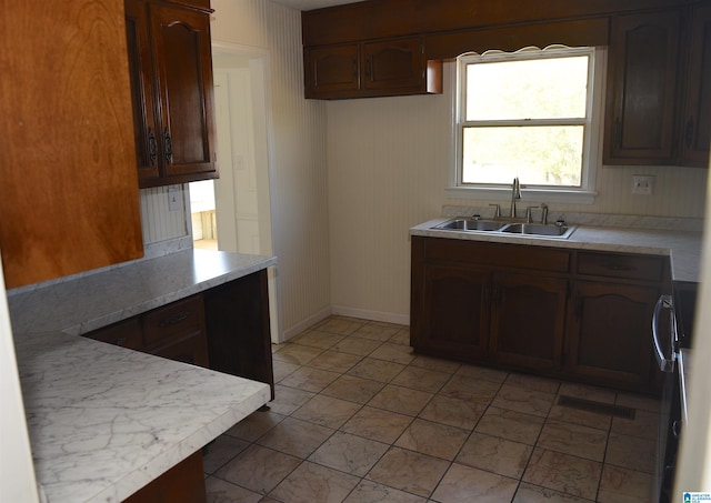 kitchen featuring sink, light tile floors, and dark brown cabinetry