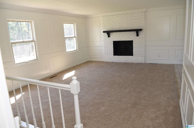 unfurnished living room with brick wall, a brick fireplace, carpet floors, and ornamental molding