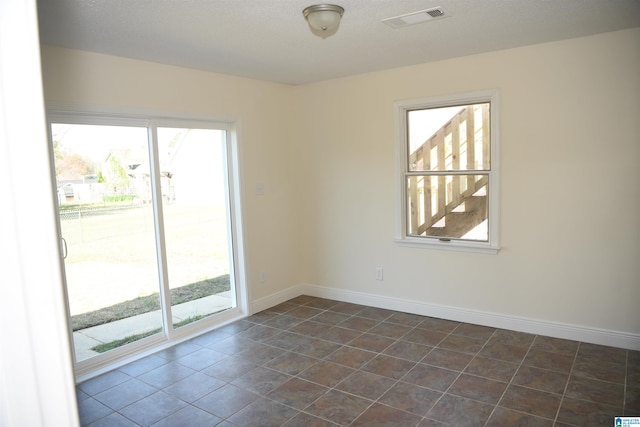 unfurnished room with dark tile flooring and a wealth of natural light