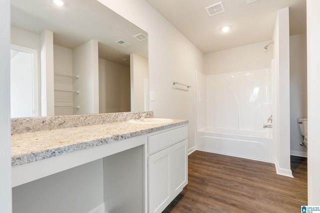 full bathroom featuring hardwood / wood-style floors,  shower combination, vanity, and toilet