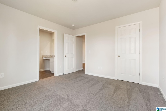 unfurnished bedroom featuring dark carpet and connected bathroom