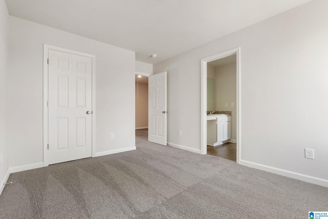 unfurnished bedroom with connected bathroom and carpet flooring