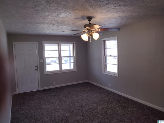 entryway with ceiling fan, dark colored carpet, and a textured ceiling