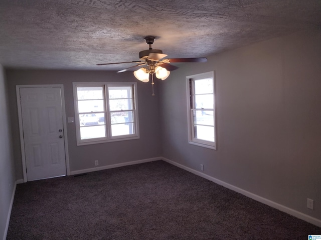 carpeted empty room with ceiling fan, a textured ceiling, and a wealth of natural light