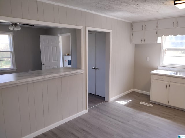 kitchen featuring a textured ceiling, white cabinets, and light hardwood / wood-style flooring