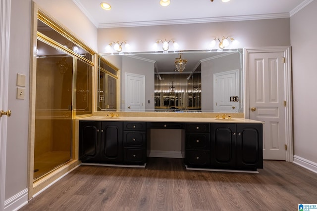 bathroom featuring double sink, vanity with extensive cabinet space, a shower with shower door, hardwood / wood-style flooring, and ornamental molding