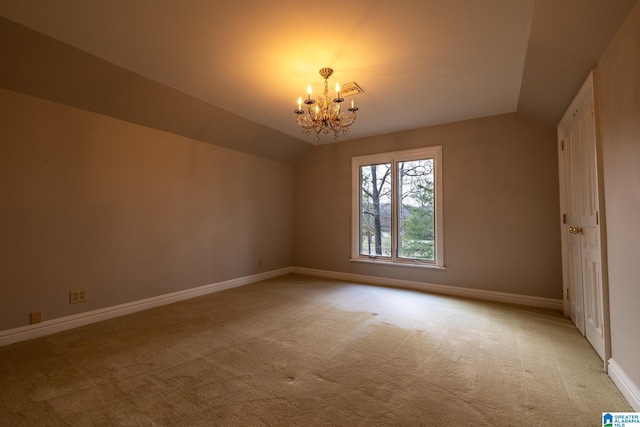 carpeted spare room with an inviting chandelier and lofted ceiling