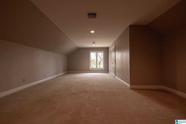 additional living space with light carpet and vaulted ceiling