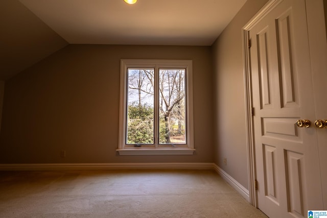 additional living space featuring light colored carpet and vaulted ceiling