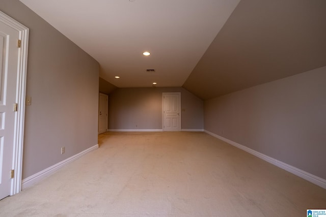 additional living space featuring light carpet and vaulted ceiling