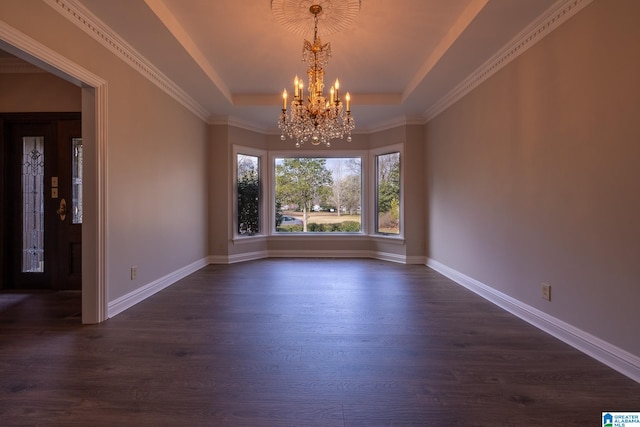 empty room featuring a raised ceiling, dark hardwood / wood-style flooring, ornamental molding, and a chandelier