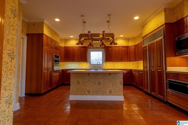 kitchen with built in appliances, ornamental molding, dark tile floors, and a center island