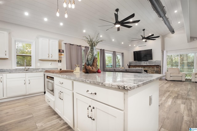 kitchen with white cabinetry, light hardwood / wood-style floors, ceiling fan, and light stone countertops