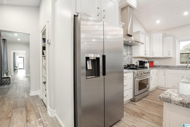 kitchen with appliances with stainless steel finishes, white cabinetry, light hardwood / wood-style flooring, and wall chimney range hood