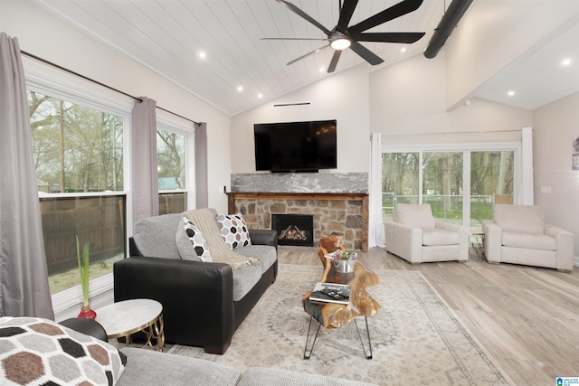 living room with ceiling fan, vaulted ceiling with beams, light hardwood / wood-style flooring, and a fireplace