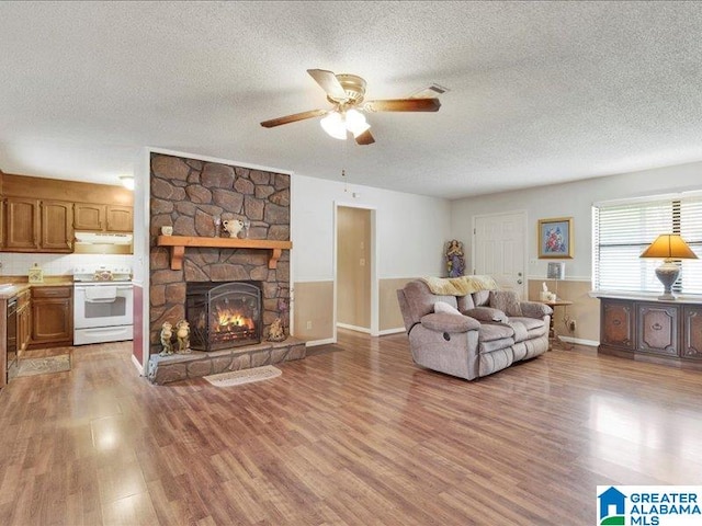 living room featuring hardwood / wood-style floors, ceiling fan, a textured ceiling, and a fireplace