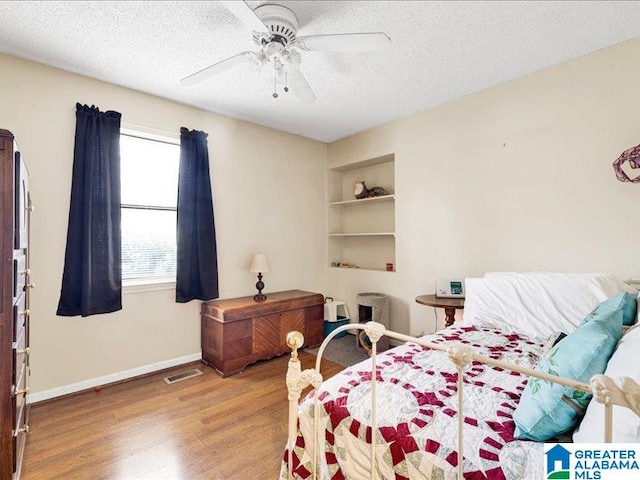 bedroom with ceiling fan, a textured ceiling, and light hardwood / wood-style floors