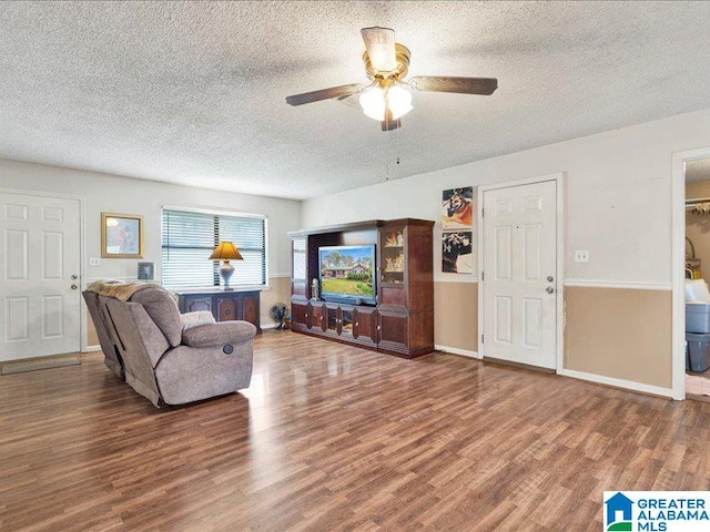 living room with ceiling fan, dark wood-type flooring, and a textured ceiling