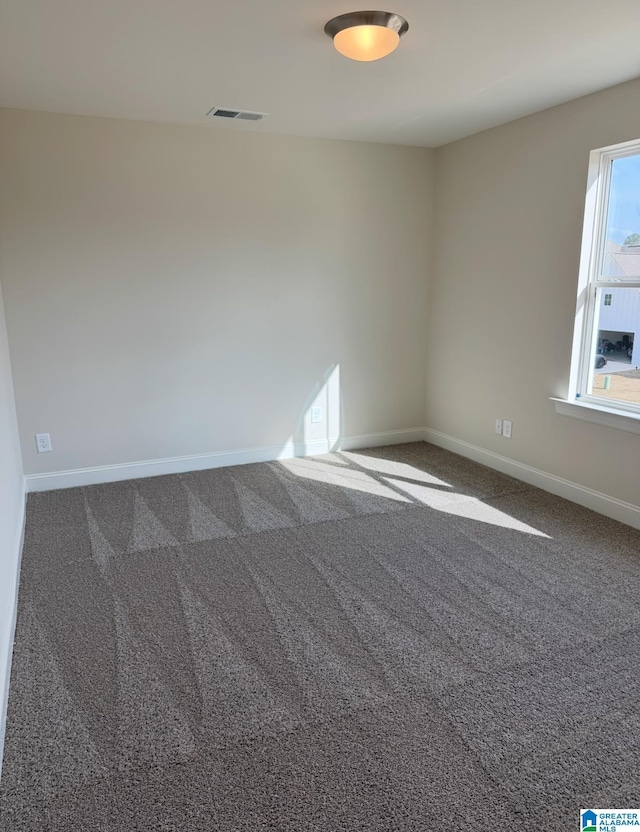 spare room with carpet, visible vents, and baseboards