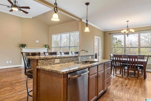 kitchen featuring light hardwood / wood-style flooring, decorative light fixtures, sink, and stainless steel dishwasher